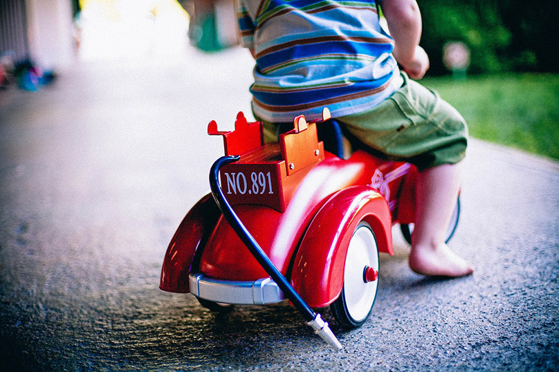 A child is riding on a toy car.