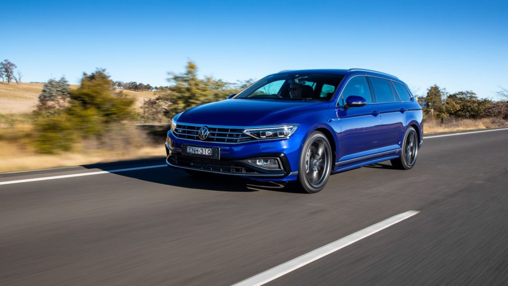 A blue Volkswagen Passat Wagon drives along a country road.