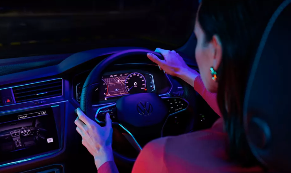 A woman drives a Volkswagen Tiguan SUV, which features interior LED lighting